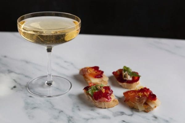Beetroot-Cured Trout with Fizzy Wine Close-up of slices of beetroot-cured trout on slices of crusty bread, served with a glass of fizzy wine.